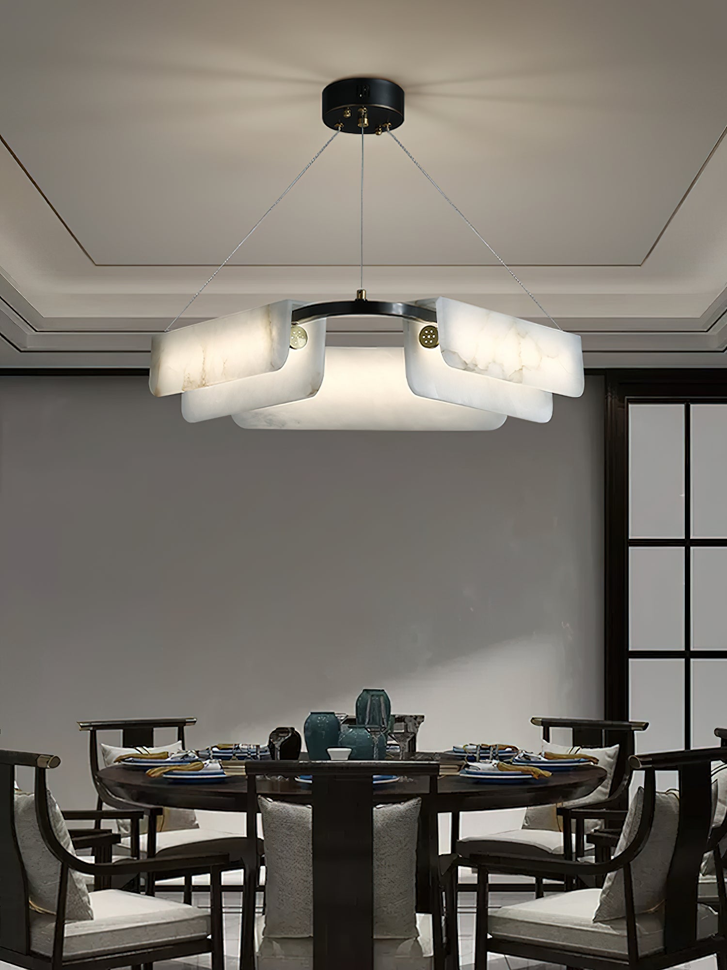 The Clérachic Layered Alabaster Plate Chandelier centred over a round dining table set for a family meal.