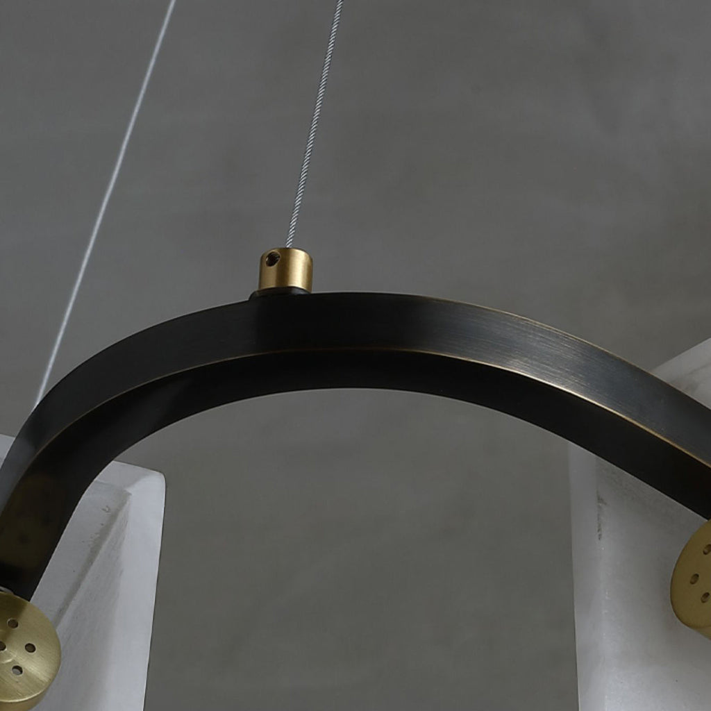 The blackened metal ring of the Clérachic Layered Alabaster Plate Chandelier, a brass grip holding the steel cable.