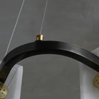 The blackened metal ring of the Clérachic Layered Alabaster Plate Chandelier, a brass grip holding the steel cable.