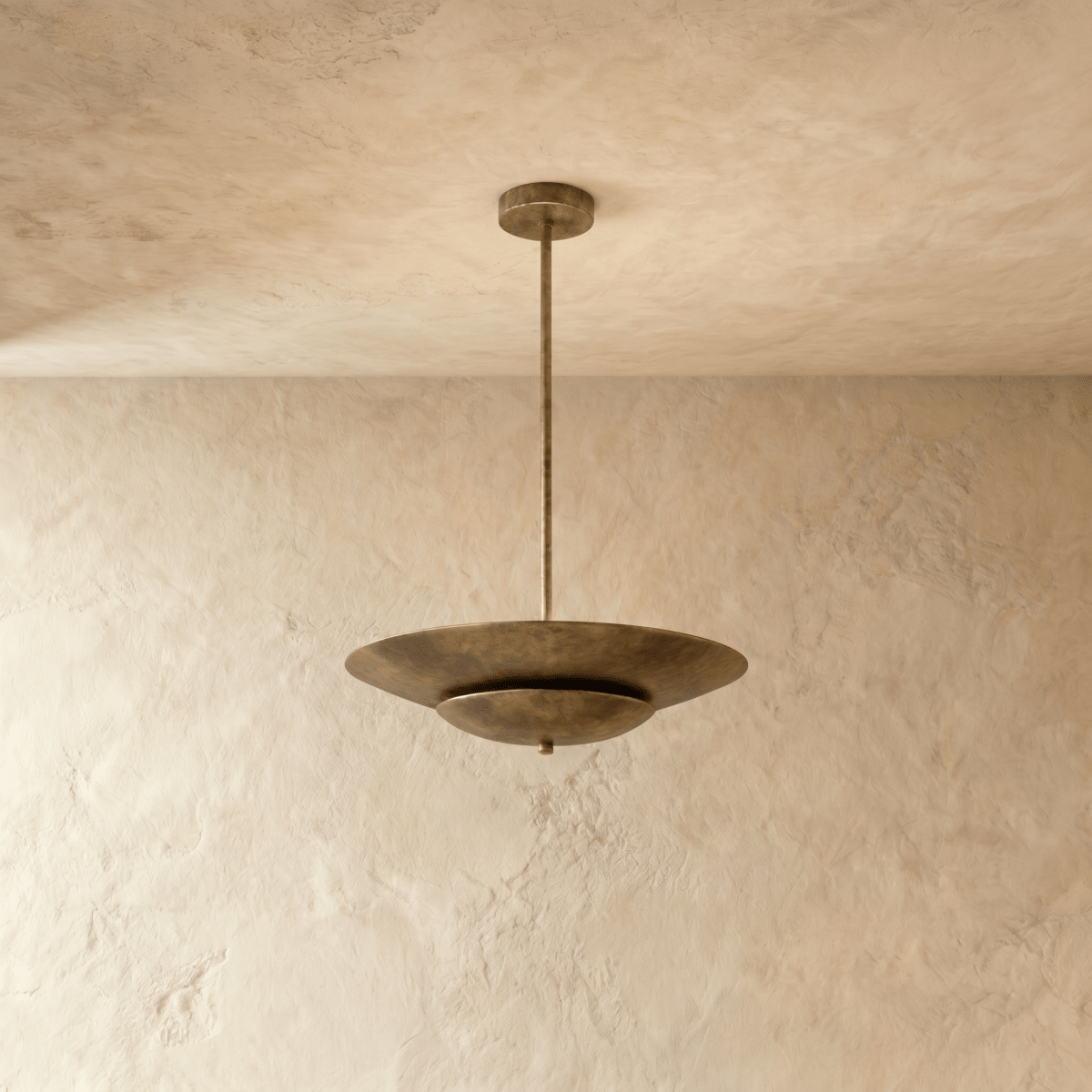 Clérachic pendant light in vintage brass, its wide disc shade suspended from a slender rod against plaster.