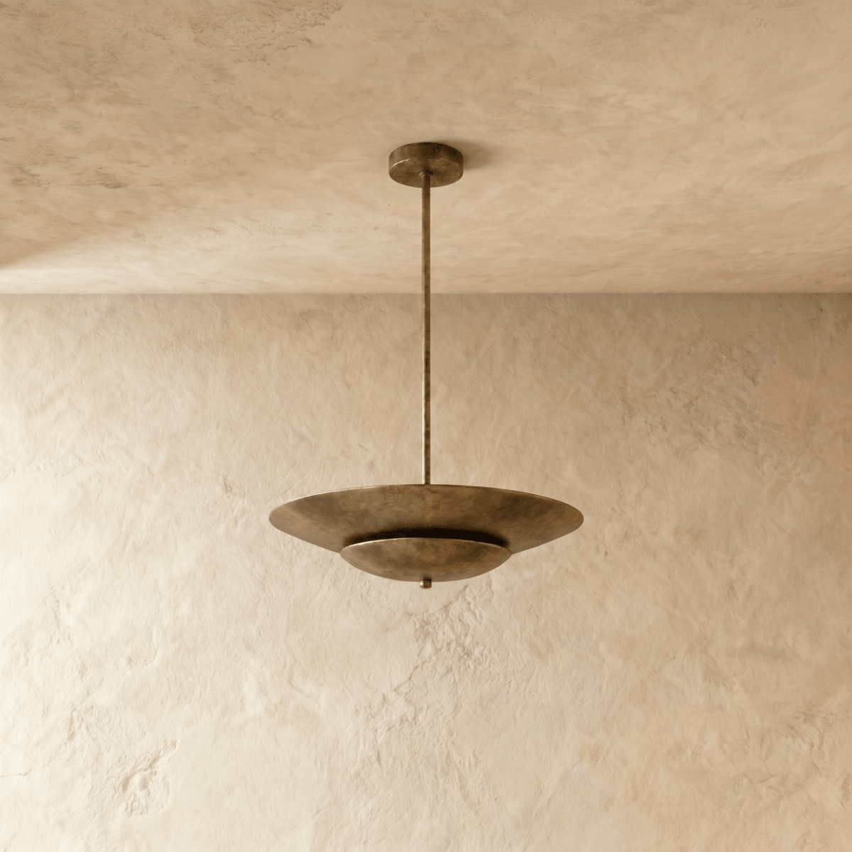Clérachic pendant light in vintage brass viewed from another angle, the layered disc shade catching soft light.