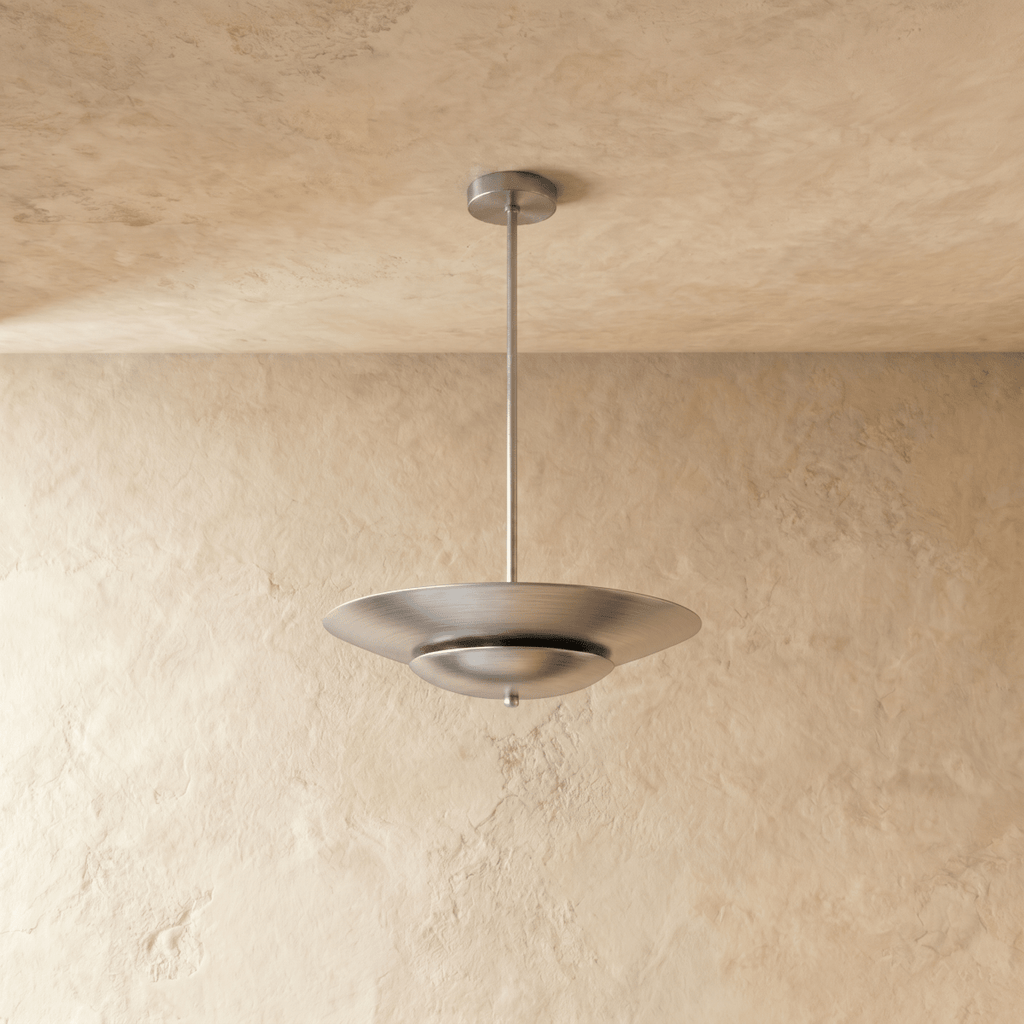 Clérachic pendant light in chrome viewed at an angle, the layered saucer shade reflecting soft ambient light.