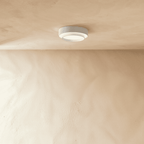 Clérachic white layered round ceiling light mounted on a plastered ceiling above a pale limewash wall, softly lit.