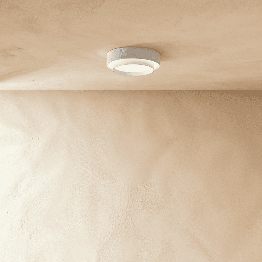 Clérachic white layered round ceiling light mounted on a plastered ceiling above a pale limewash wall, softly lit.