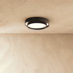 Clérachic black layered round flush ceiling light with a frosted lit centre, mounted on a plastered ceiling.