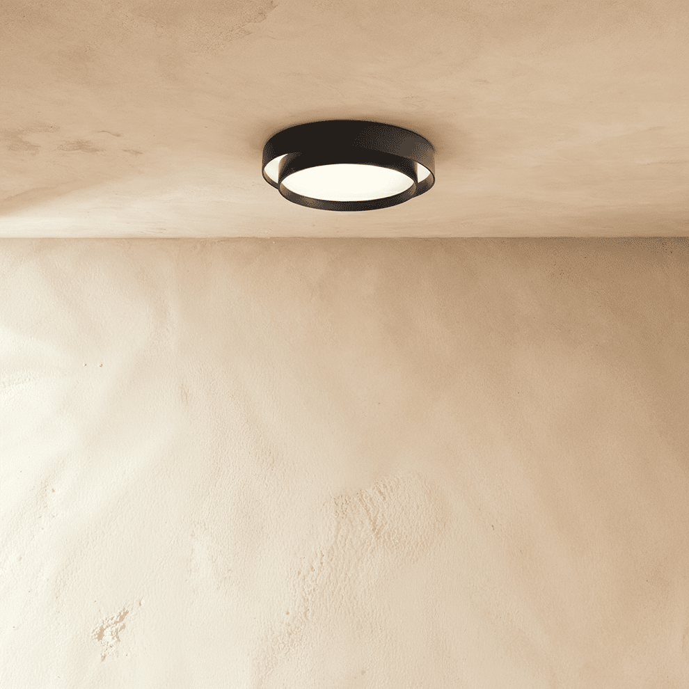 Clérachic black layered round ceiling light set high on a plastered ceiling above a pale limewash wall.