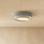 Clérachic grey two-tier round ceiling light with a white inner drum and soft central glow on a limewash ceiling.