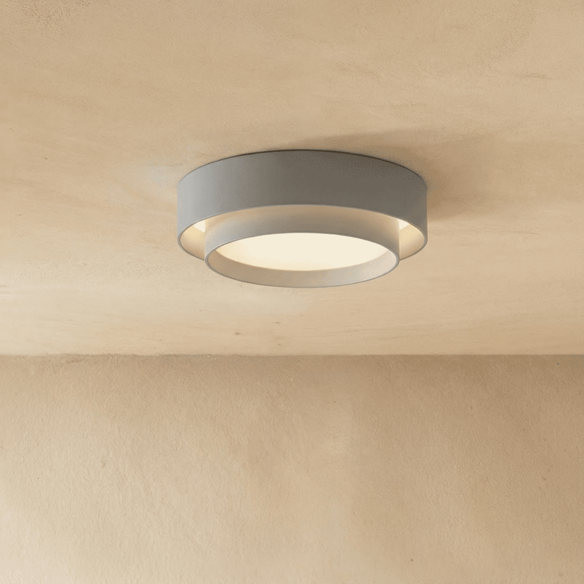 Clérachic grey two-tier round ceiling light with a white inner drum and soft central glow on a limewash ceiling.