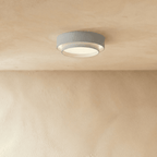 Clérachic grey layered round flush ceiling light with a pale inner ring, softly lit on a plastered ceiling.
