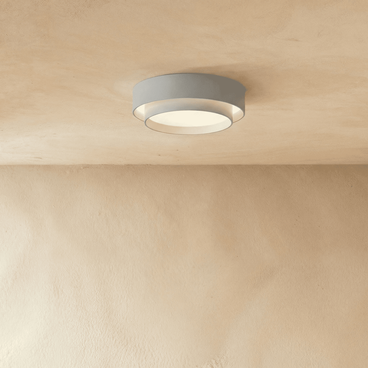 Clérachic grey layered round flush ceiling light with a pale inner ring, softly lit on a plastered ceiling.