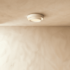Clérachic white layered round ceiling light with a warm lit centre, mounted on a plastered ceiling above a limewash wall.