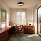 Clérachic black layered round ceiling light centred over a walnut corner desk in a sunlit home office with sheer curtains.