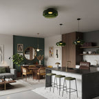 A green glass Clérachic ceiling light in an open-plan kitchen and dining area, with two pendants and a dark island.