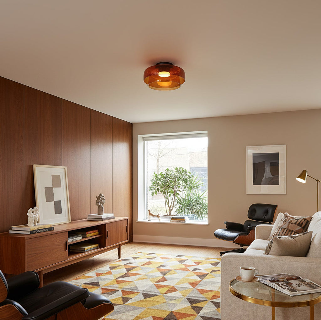 An orange glass Clérachic ceiling light over a living room with a walnut wall, a sideboard and a geometric rug.