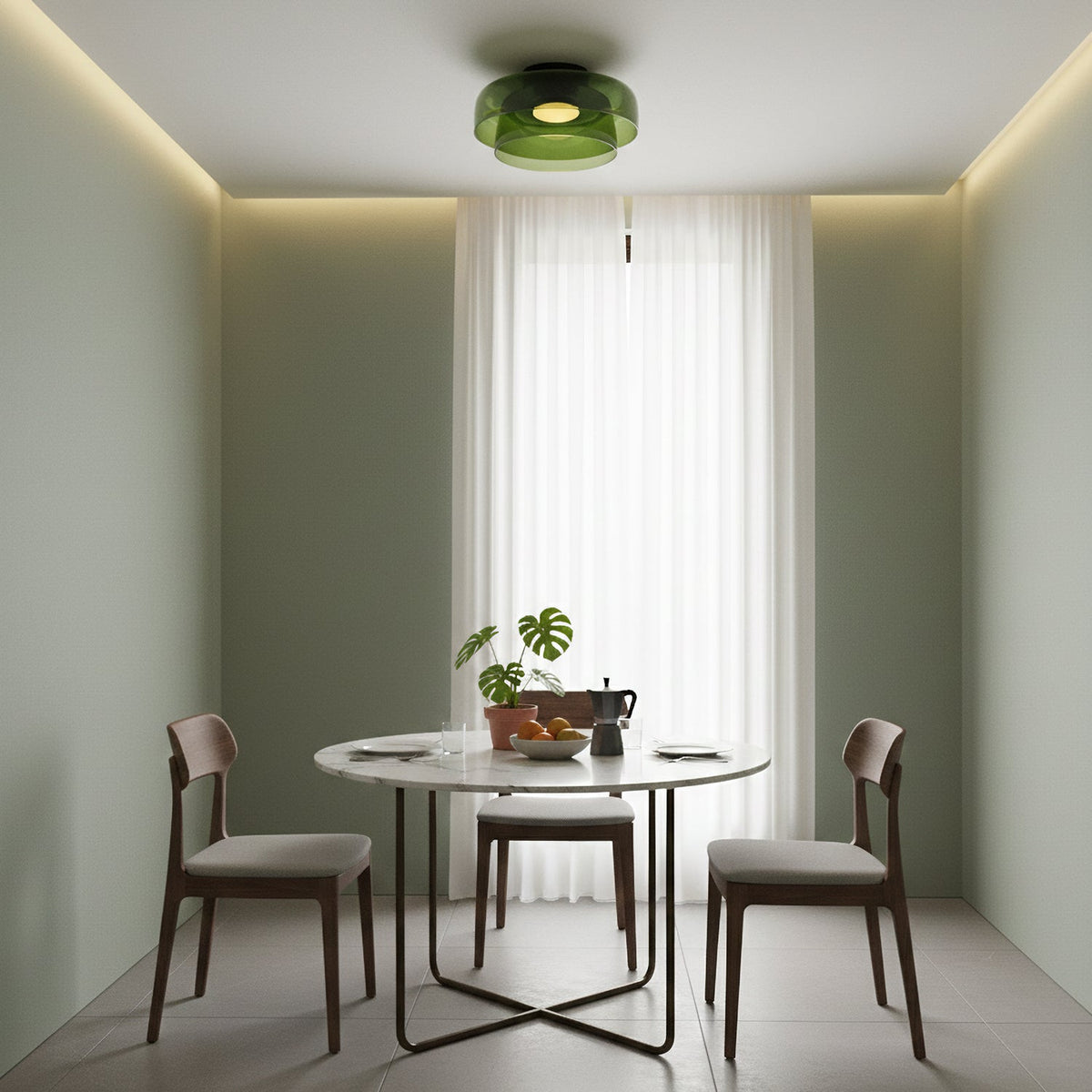A green glass Clérachic ceiling light above a round dining table, with a sage-green alcove and a sheer white curtain.