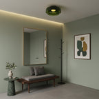 A green glass Clérachic ceiling light in a sage-green entrance with a framed mirror, a bench and a coat stand.