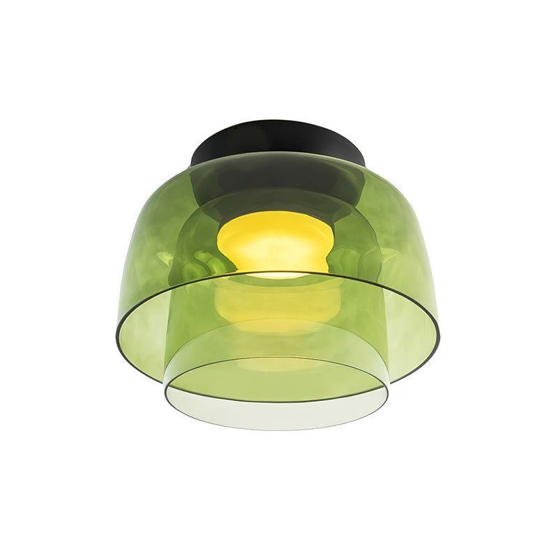 A taller green glass Clérachic ceiling light with two nested layers, lit, on a white backdrop.