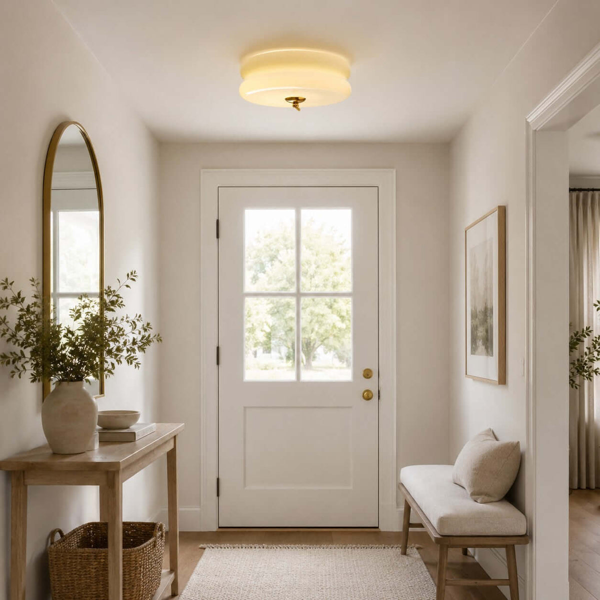 Clérachic flush mount lit above a hallway with a white glazed door, an arched mirror, a console table and a bench with a basket.