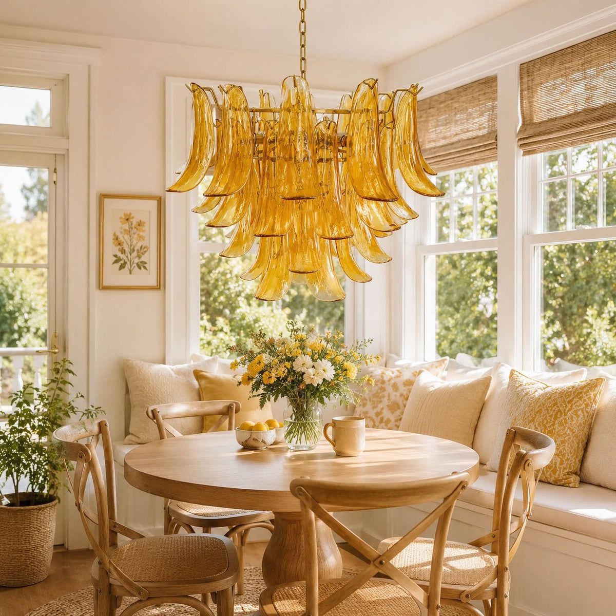 An amber glass leaf chandelier hangs above a round wooden table in a sunny breakfast nook with a window seat, from Clérachic.