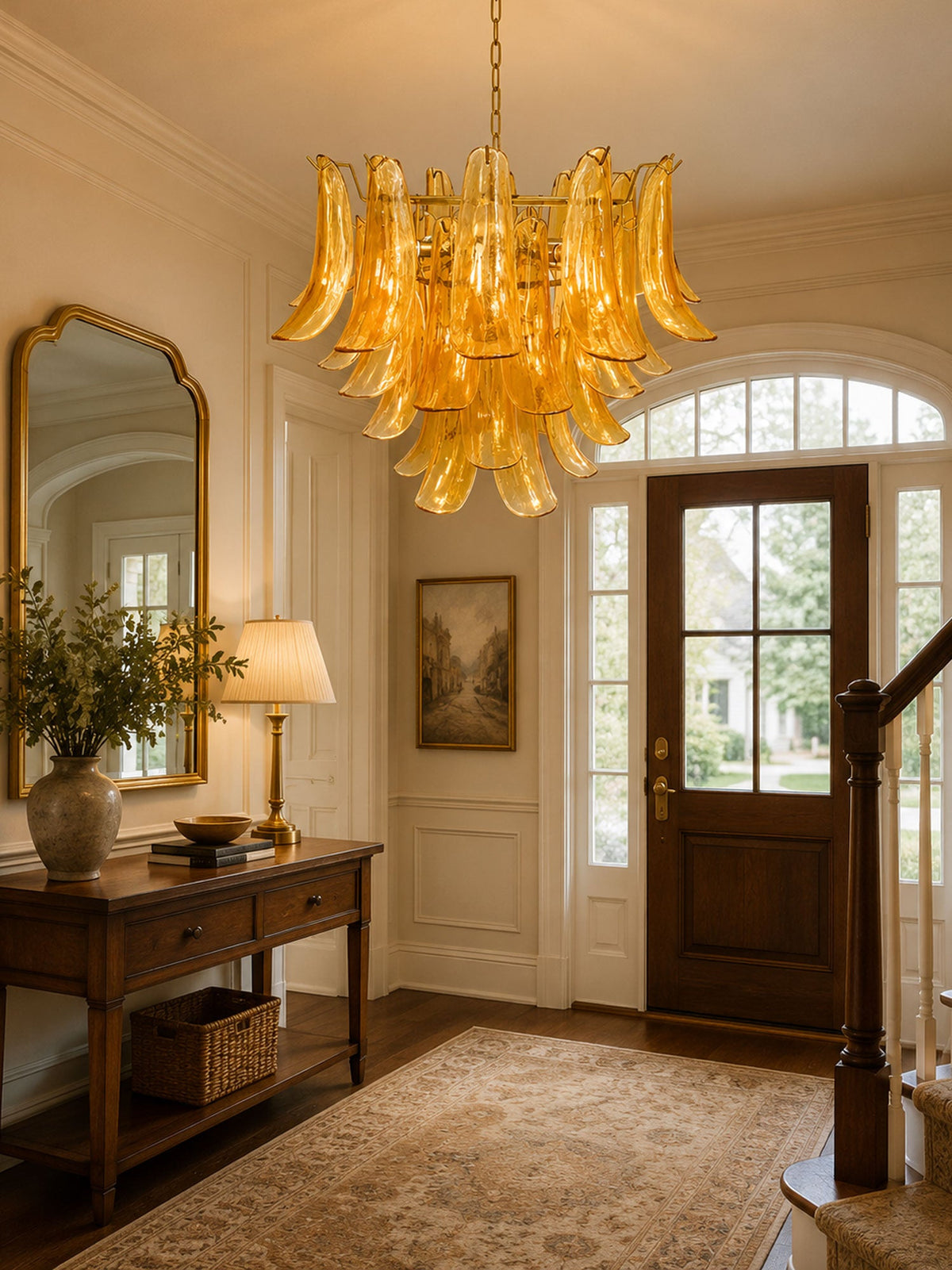 Amber glass leaf chandelier from Clérachic lighting a hallway with an arched mirror, a wooden console and a panelled front door.