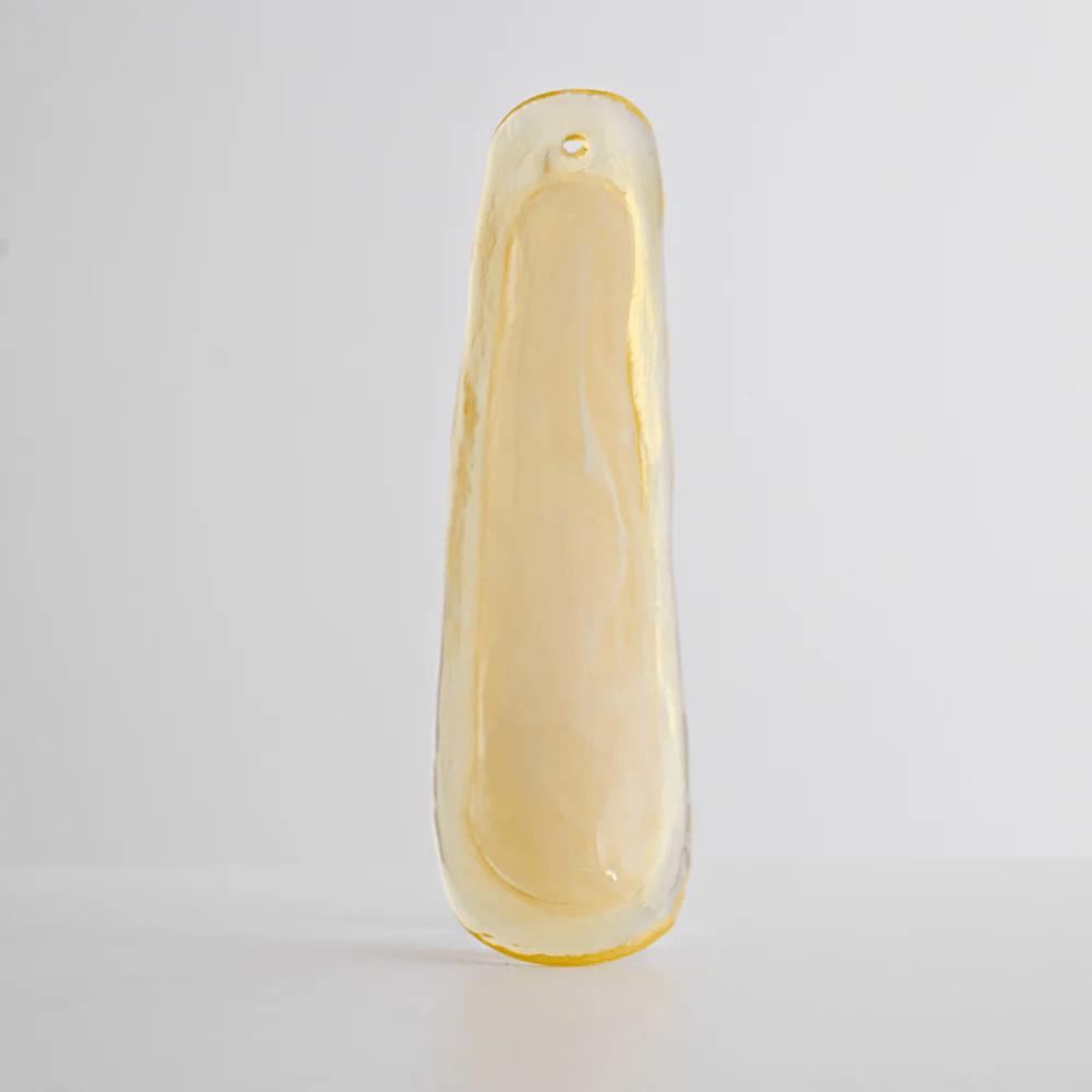 Single pale yellow glass leaf with a smooth, thick edge, shown upright on a light grey backdrop as part of this Clérachic chandelier.