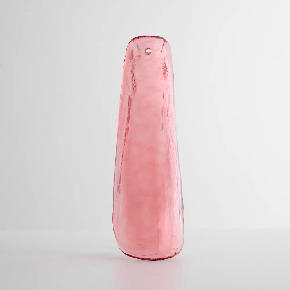 Rosy pink glass leaf with a rippled surface, standing on a pale grey surface, one of the glass options for this Clérachic chandelier.