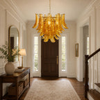 Seen from a hallway entrance, an amber glass leaf chandelier from Clérachic hangs in front of a dark wooden door and a patterned runner.