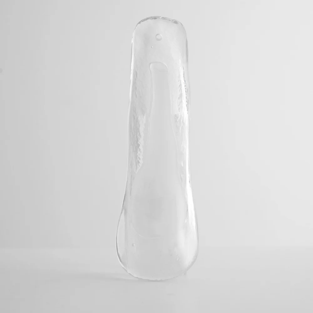 Clear glass leaf with a frosted streak through its middle and a small hole at the top, shown on grey for this Clérachic chandelier.