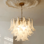 Frosted white glass leaf chandelier from Clérachic on a brass canopy, hung under a carved ceiling rose in a sunlit room.