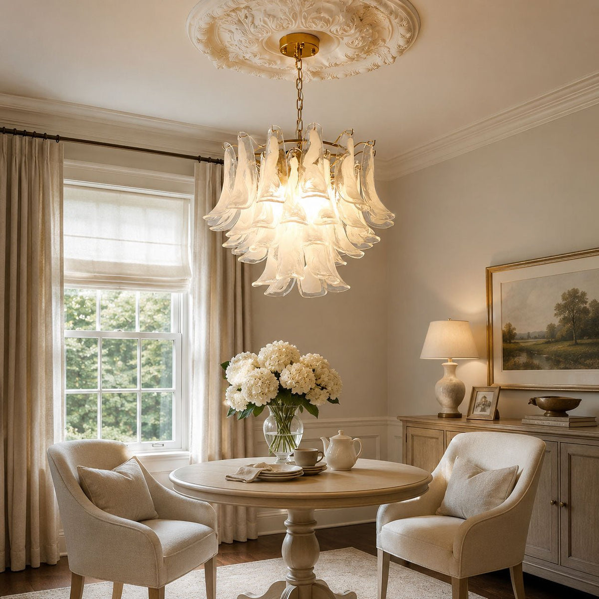 This Clérachic white glass leaf chandelier hangs near a tall window, over a small round table with two armchairs and a teapot.
