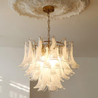 Frosted white cloud glass leaves light up on this Clérachic chandelier, hanging from a brass canopy under a plaster ceiling rose.
