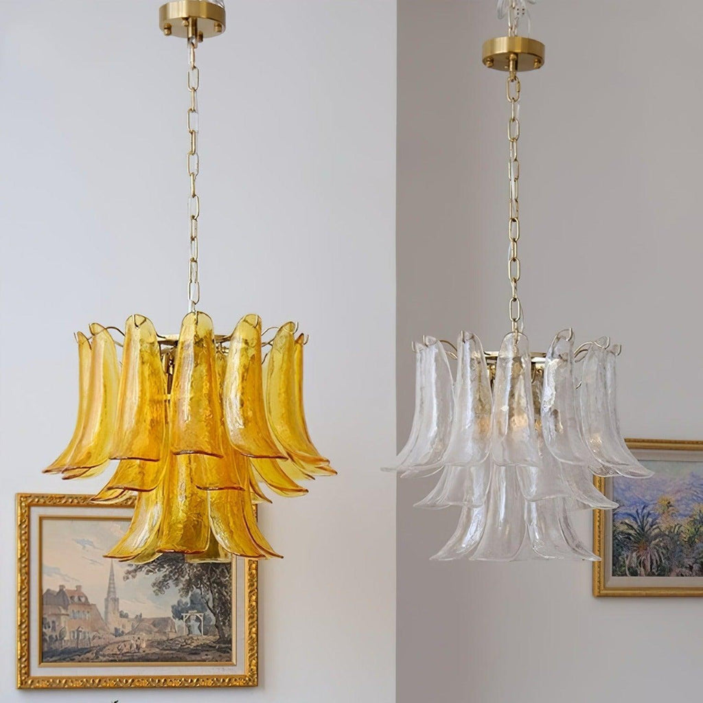 Two Clérachic chandeliers side by side, one in amber glass and one in clear glass, each hanging from a brass canopy on a chain.
