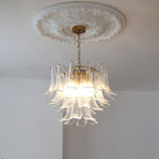 Clérachic clear glass leaf chandelier lit warm white, hanging from a brass canopy under a round plaster ceiling rose.