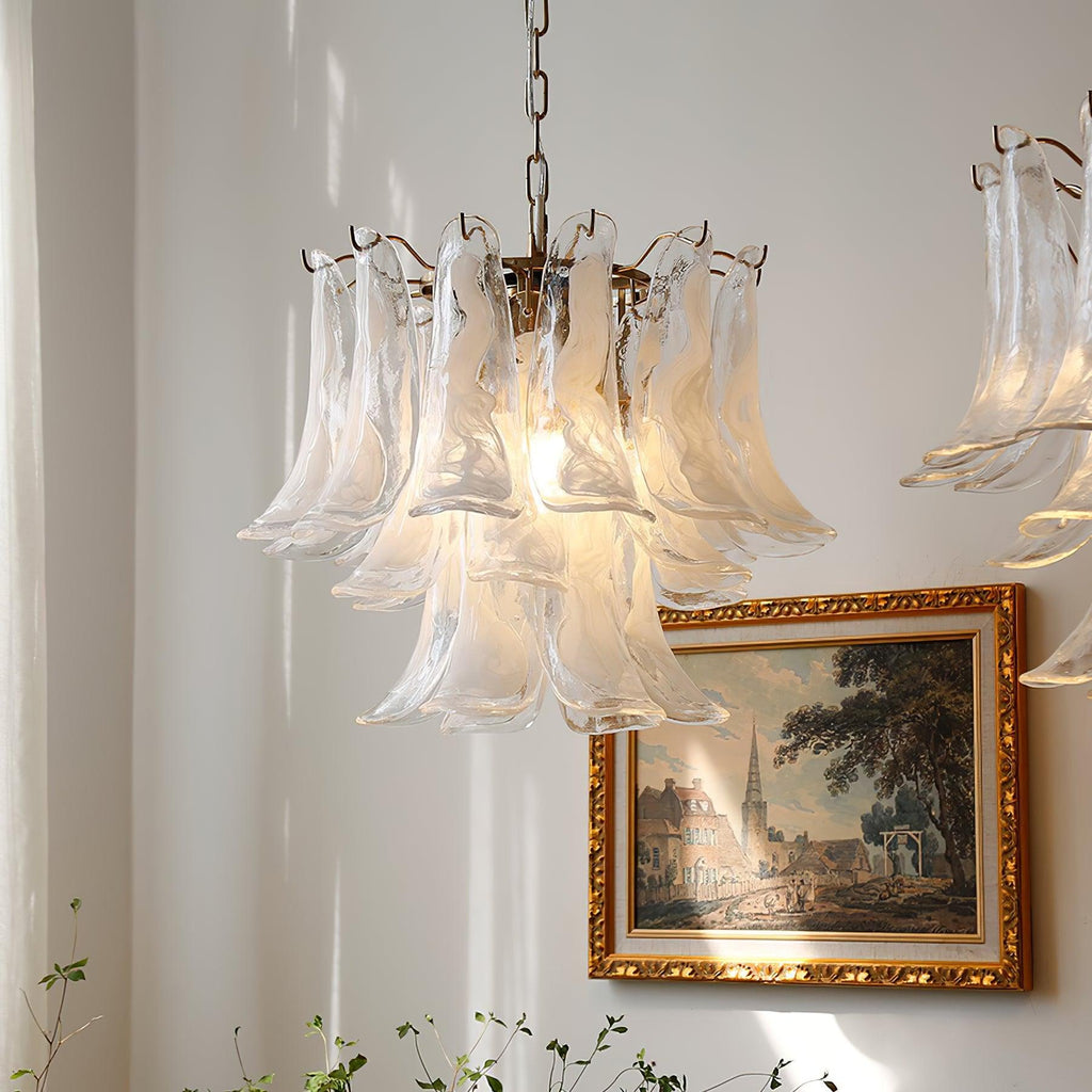Frosted glass leaves of this Clérachic chandelier glow in a pale room, with a gold-framed townscape painting below.