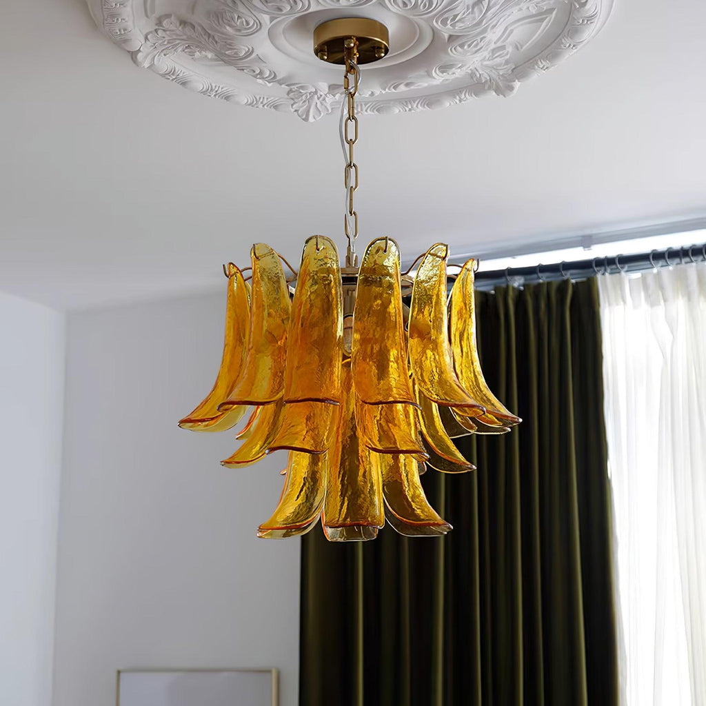 Amber glass leaf chandelier from Clérachic seen from below, with olive-green curtains and a plaster ceiling rose behind it.