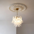 Small white cloud glass chandelier from Clérachic hanging from a short brass canopy on a ceiling with a carved plaster rose.