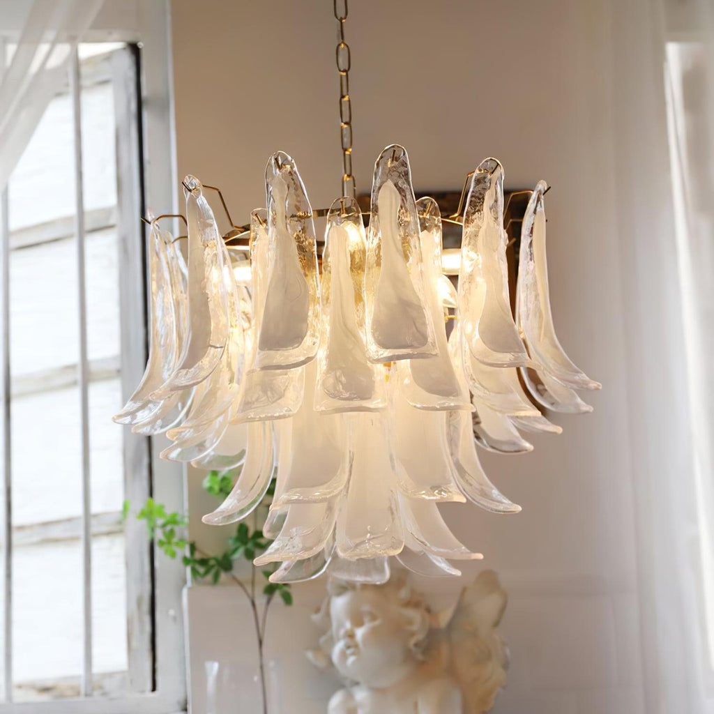 Frosted glass leaves of this Clérachic chandelier glow beside a white-framed window, with a small cherub figure beneath.