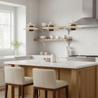 Three small cream Clérachic pendants hang in a row above a pale kitchen island, with white tiles and open shelves behind.