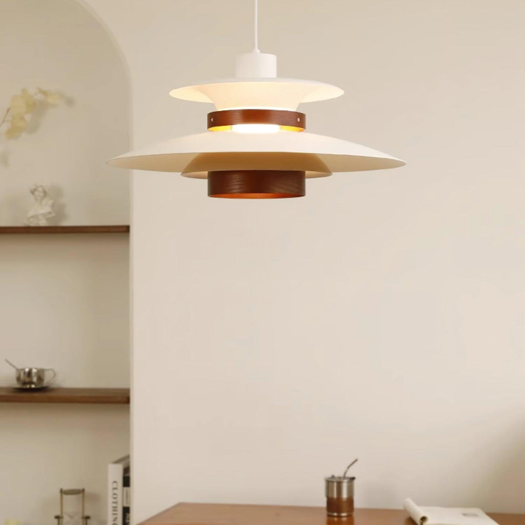 Close view of a white Clérachic pendant with a dark oak band and wood lower cylinder, glowing against a cream wall.