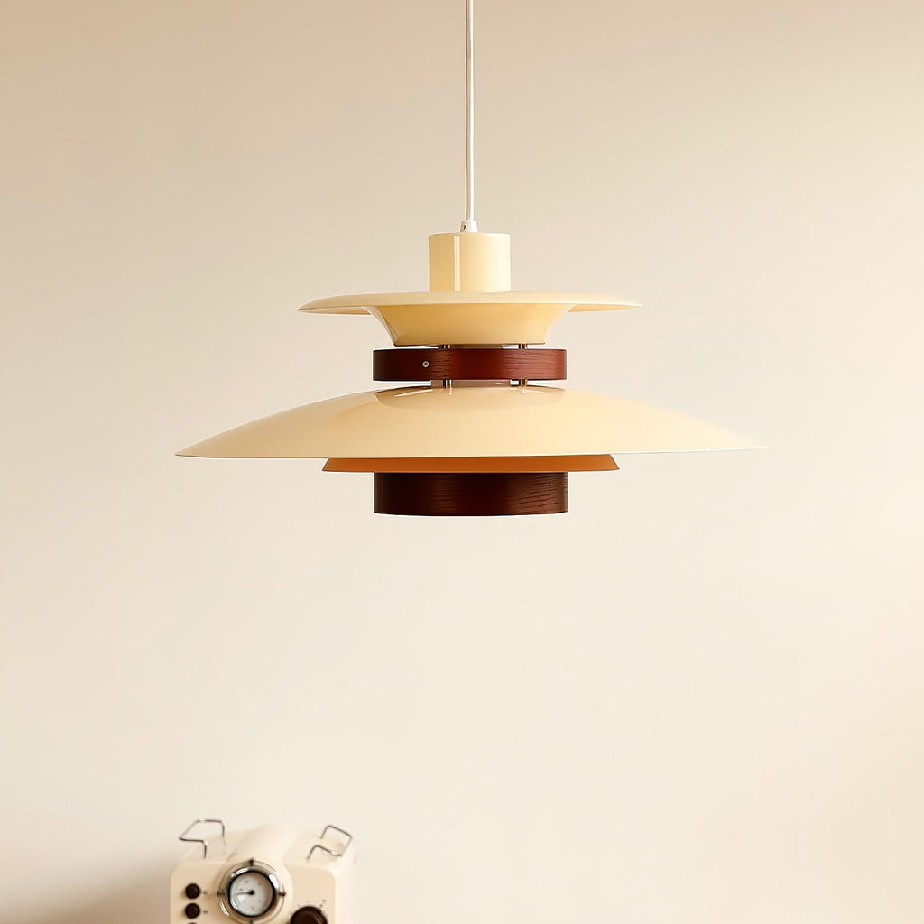 Beige Clérachic pendant with a dark oak band, hung against a plain wall with a retro coffee machine below.