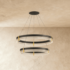 Angled view of the Clérachic two-tier ring chandelier shows both black bands glowing warmly against plaster walls.