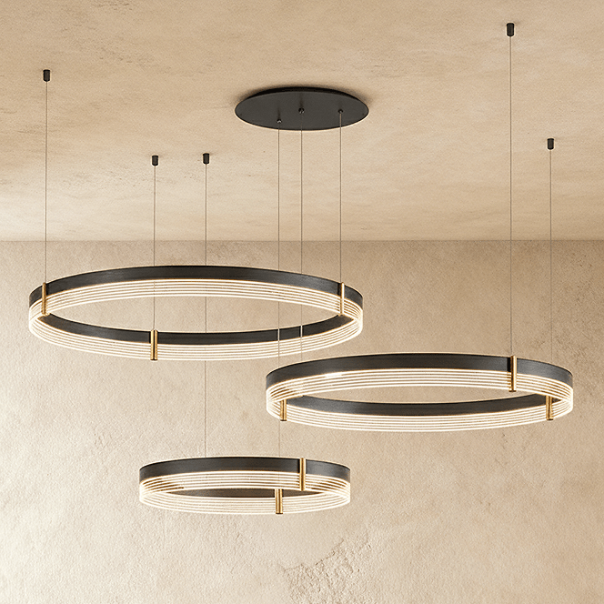 Three individual Clérachic ring pendants hang at staggered heights, each a black band lit with warm ribbed light.