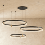 Three individual Clérachic ring pendants hang at staggered heights, each a black band lit with warm ribbed light.