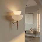 Clérachic wall lamp in brass lighting a plastered archway near a console table and abstract print.