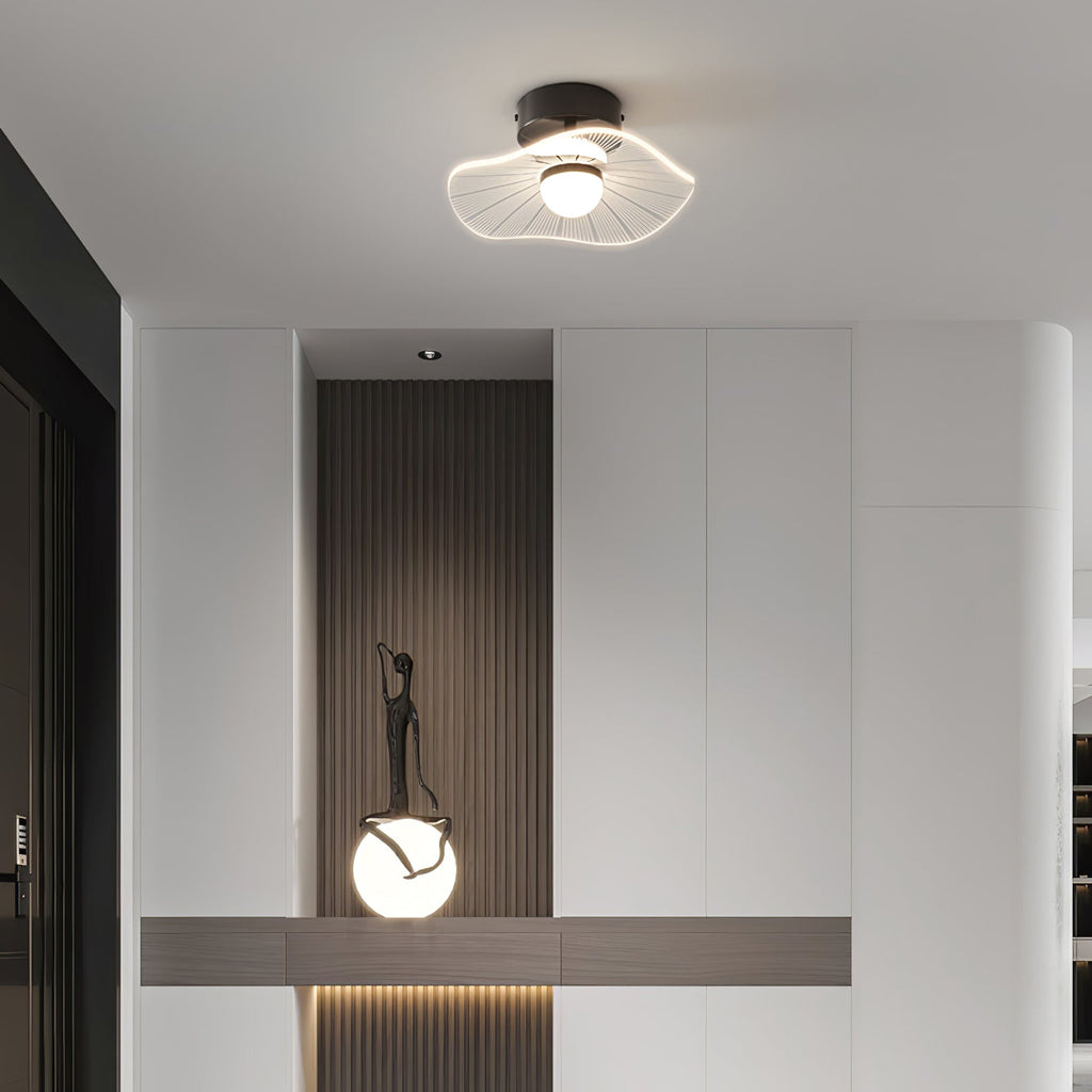 Black-based ceiling light above a hall console with a dark slatted panel and a round glowing lamp, from Clérachic.
