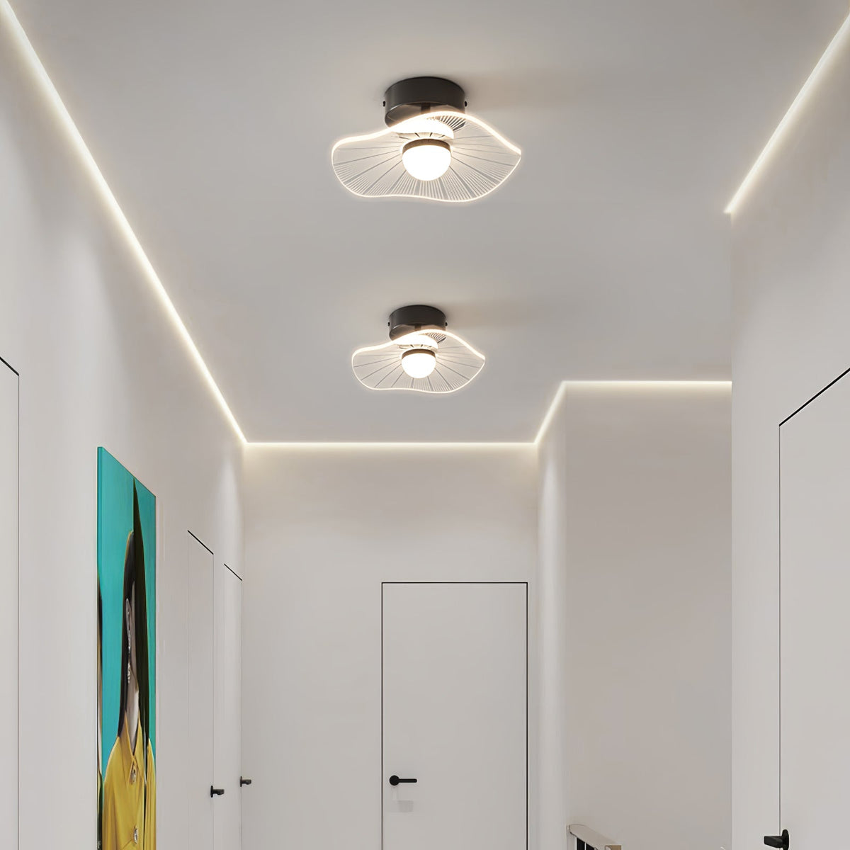 Two lit ceiling lights with wavy shades in a hallway edged with a strip of warm light, from Clérachic.