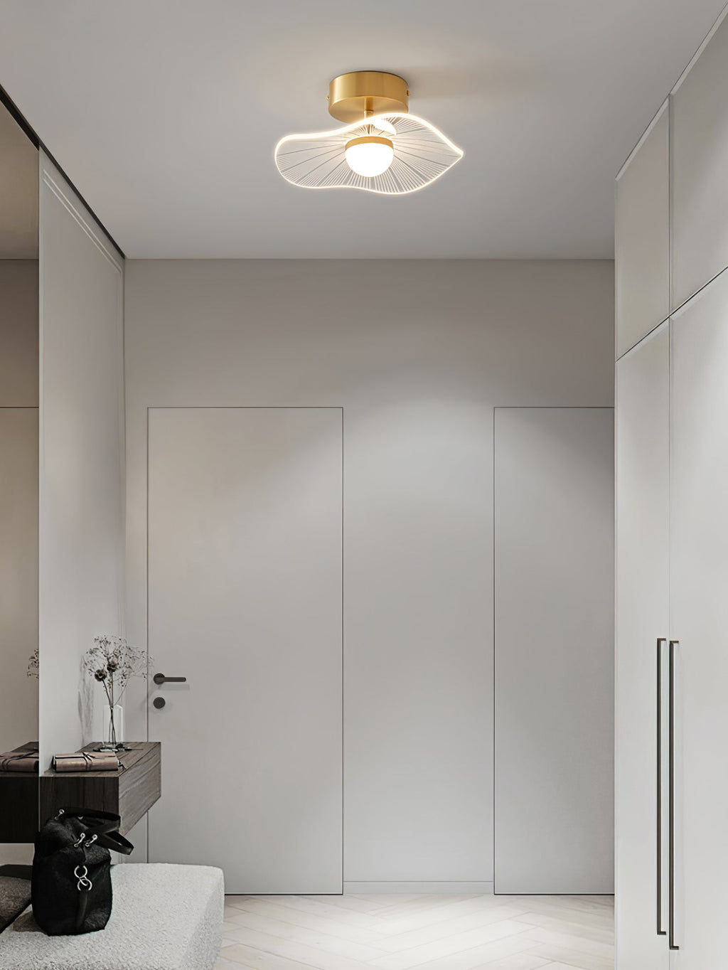 Brass-fitted ceiling light glowing in an entry hall with tall doors, built-in cupboards and a pale bench, from Clérachic.