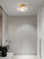 Brass-fitted ceiling light glowing in an entry hall with tall doors, built-in cupboards and a pale bench, from Clérachic.
