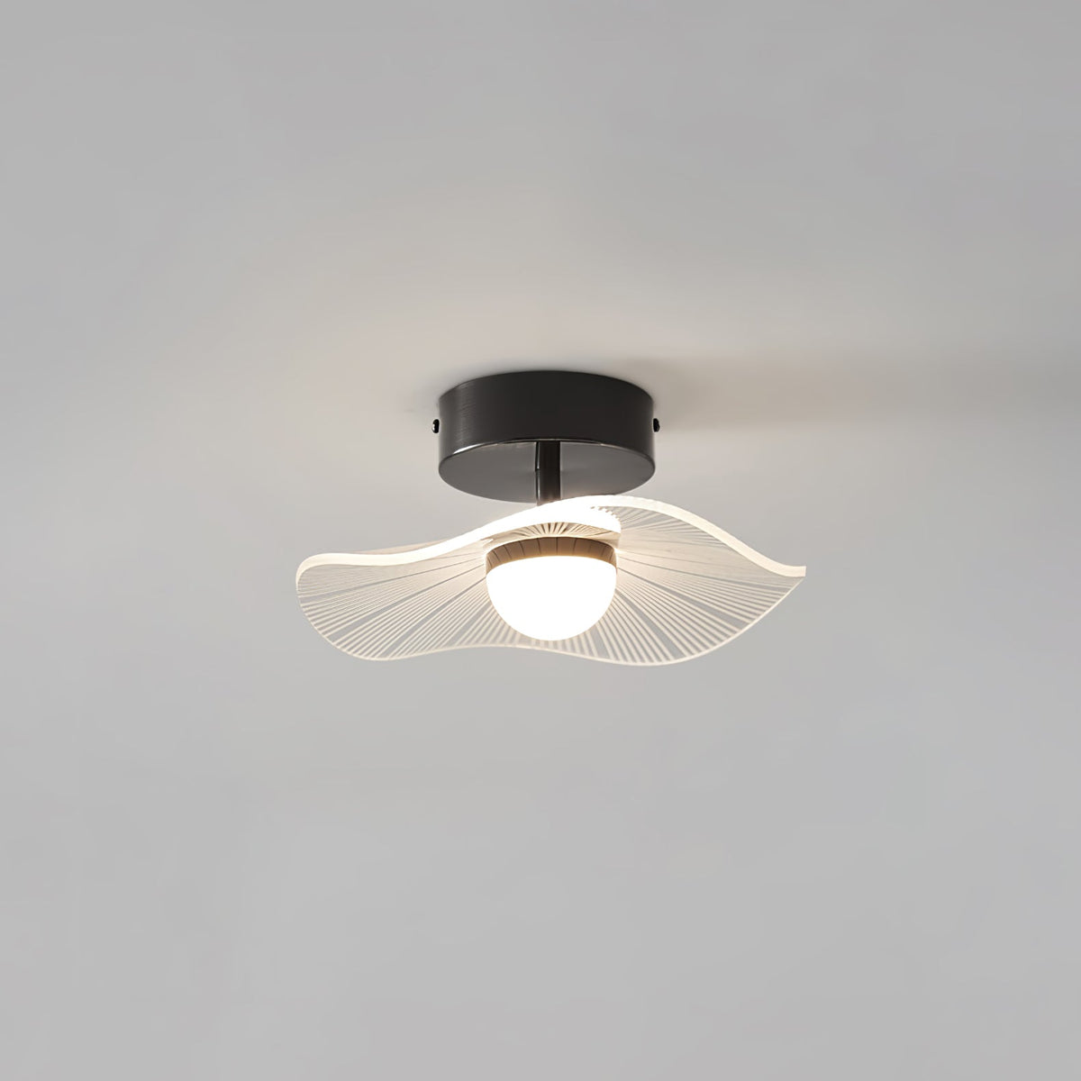 Black-fitted ceiling light with a frilly ribbed acrylic shade and a round opal bulb, on a grey ceiling, from Clérachic.