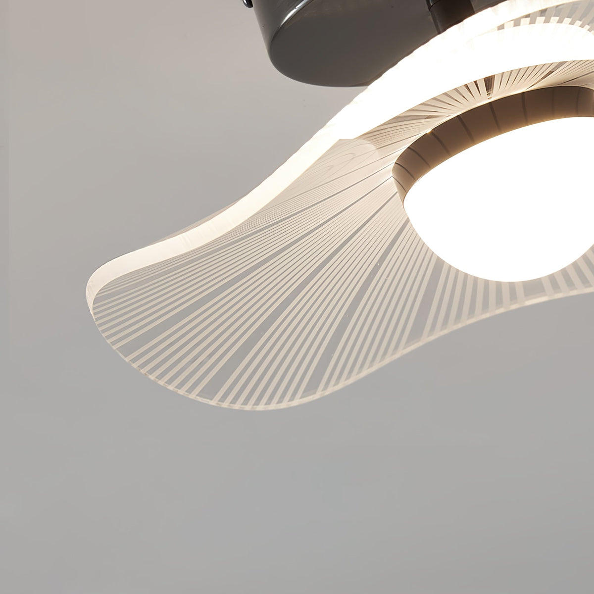 Close view of the ribbed acrylic shade, with a fan of fine lines around the glowing globe, on this Clérachic ceiling light.